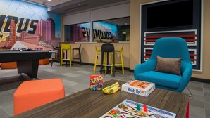 A modern lounge area with a pool table, colorful seating, and various board games. - Tru by Hilton Columbus Airport (Columbus)