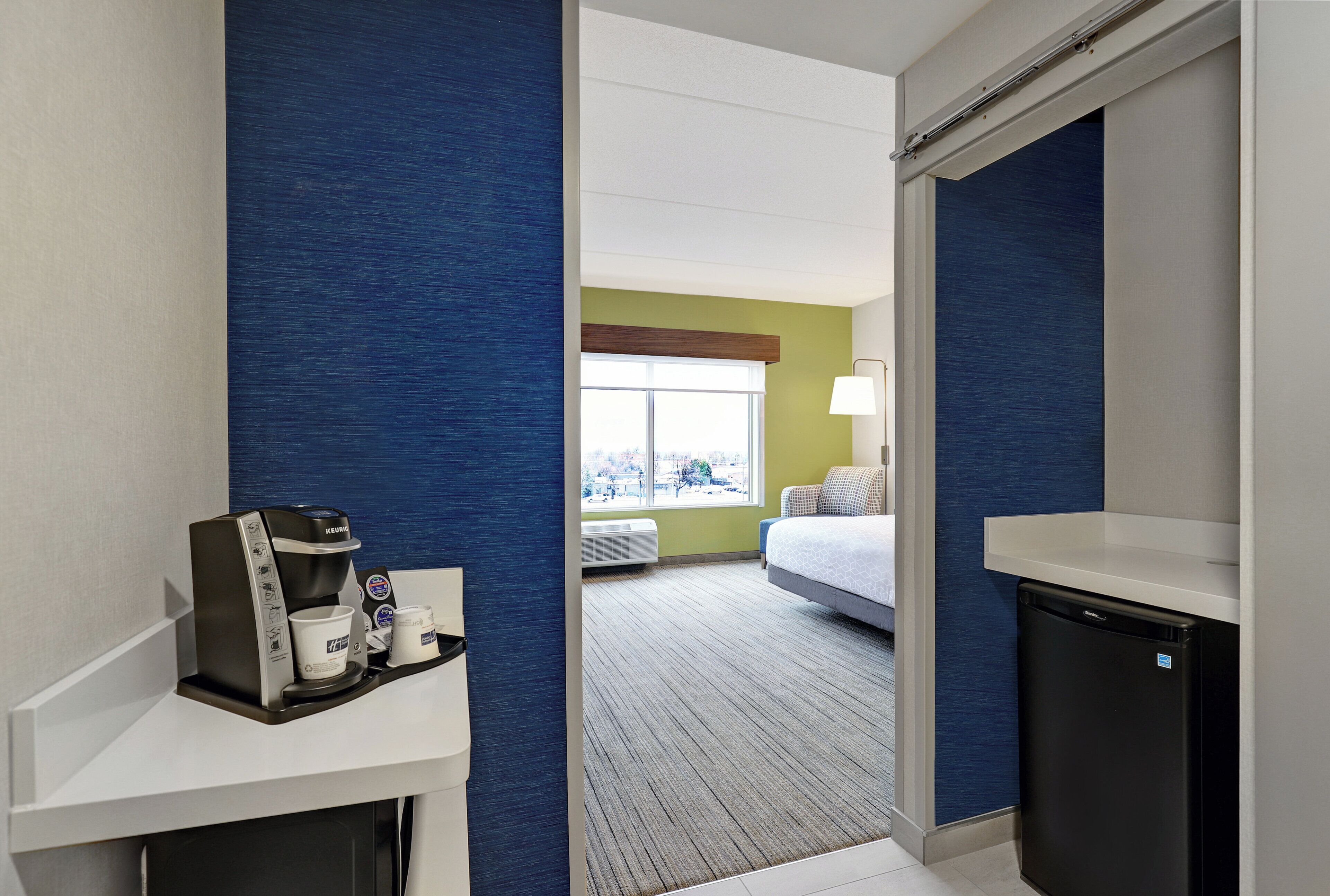 Una camera d'albergo con angolo cottura, un letto, una finestra vista e bagno.