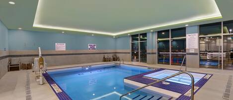 Una piscina interior con señalización clara, solárium con baldosas y diseño moderno del techo.