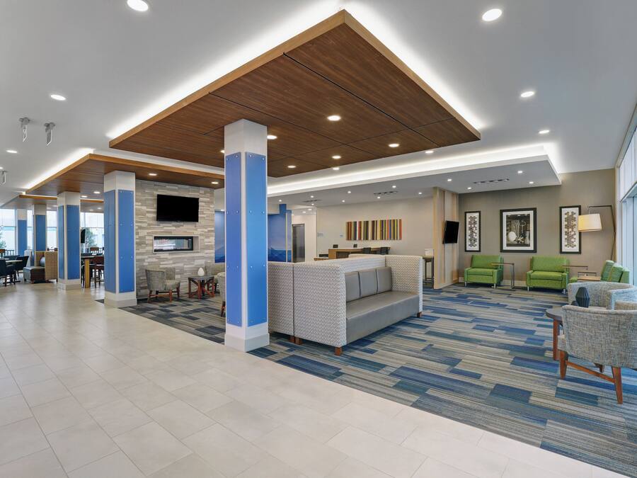 Un hall d’entrée spacieux avec un plafond haut, un espace salon central et un téléviseur fixé au mur.
