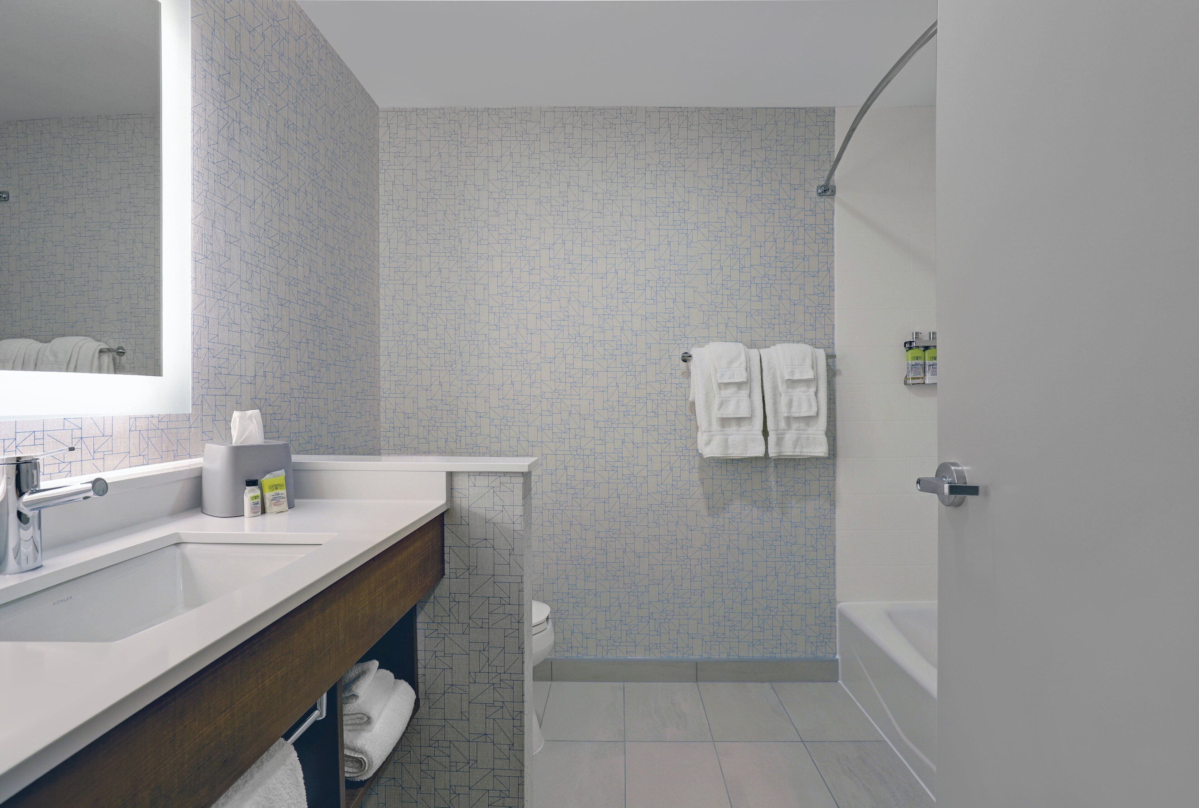A modern bathroom with a large mirror, a sink, a toilet, and a shower area.