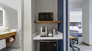 Habitación de hotel compacta con kitchenette, que incluye microondas, cafetera y refrigerador pequeño.