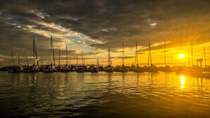 Un puerto deportivo con varios veleros amarrados bajo un cielo al atardecer.