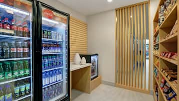 A beverage cooler with various drinks, a snack shelf with packaged goods, and a wooden partition.