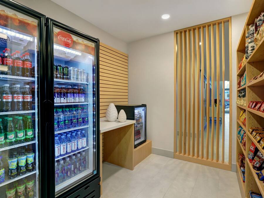 A beverage cooler with various drinks, a snack shelf with packaged goods, and a wooden partition.
