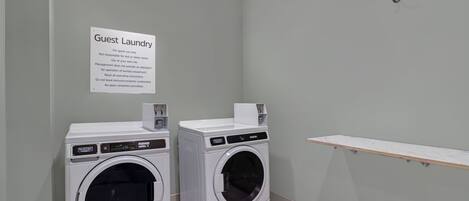 A guest laundry area with two washing machines and a sign providing instructions.