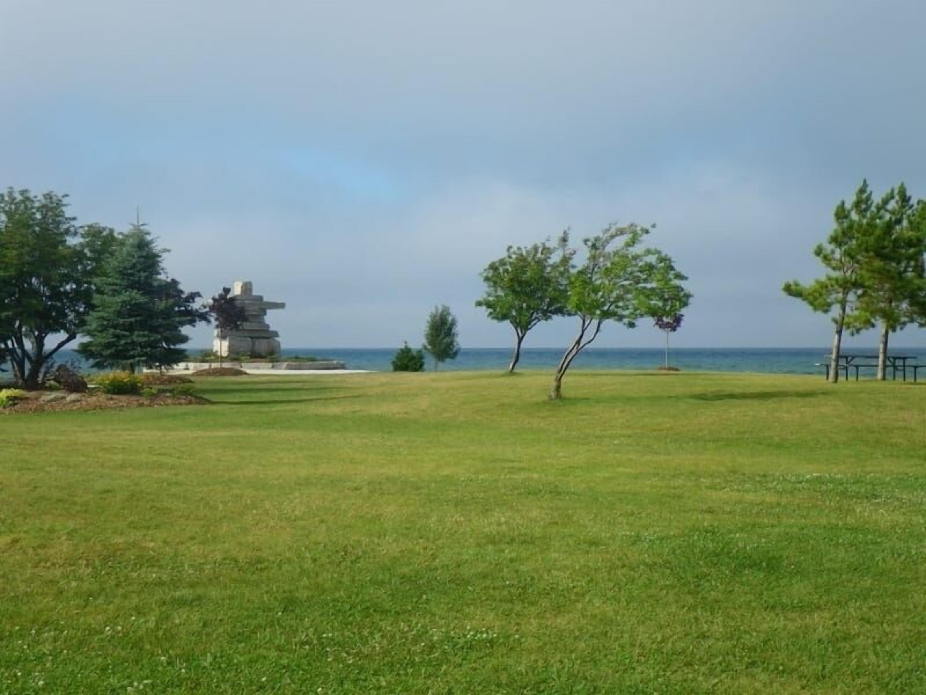 A grassy park area with a stone monument and trees.
