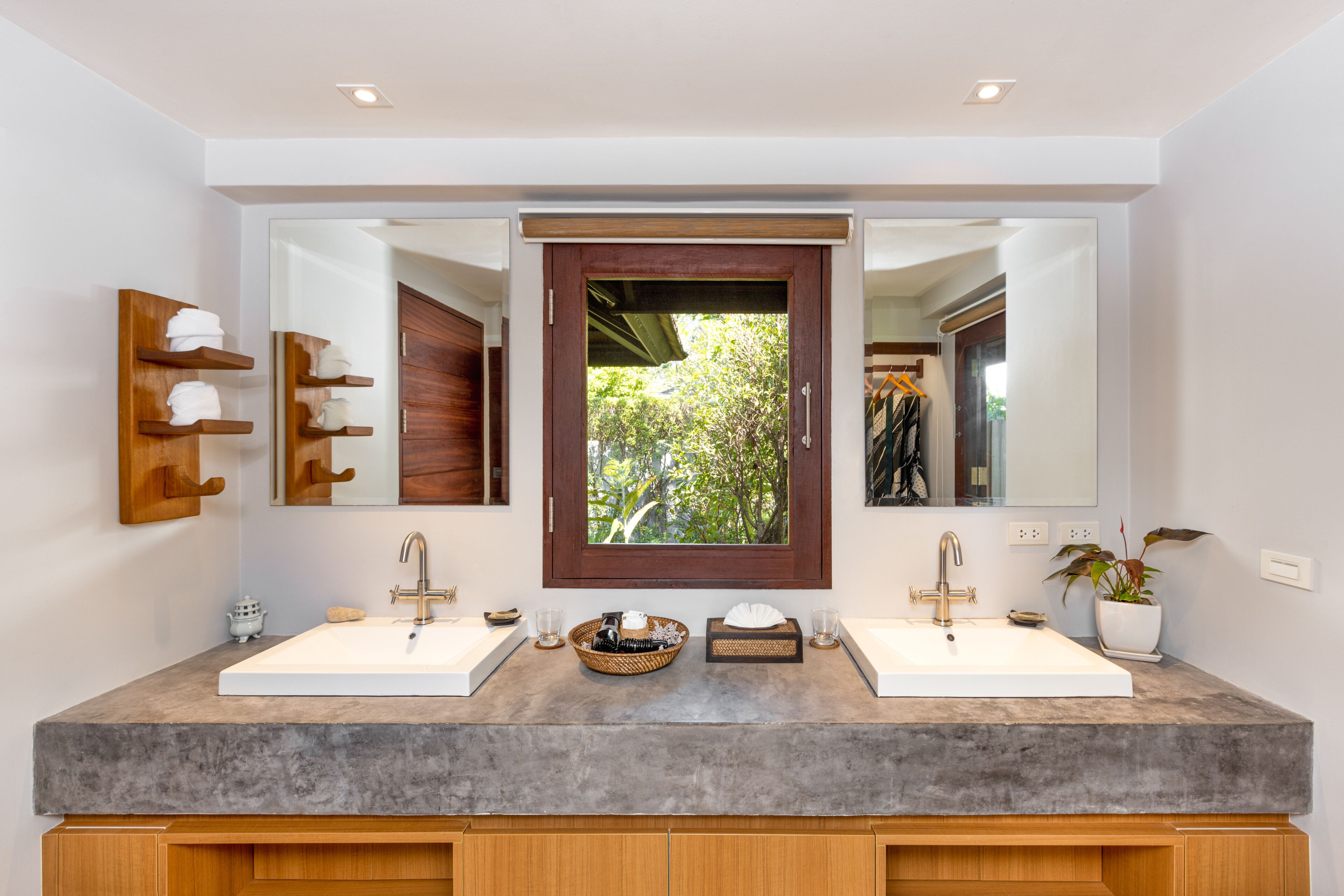 Un baño moderno con dos lavamanos, un espejo grande y vistas a zonas verdes.
