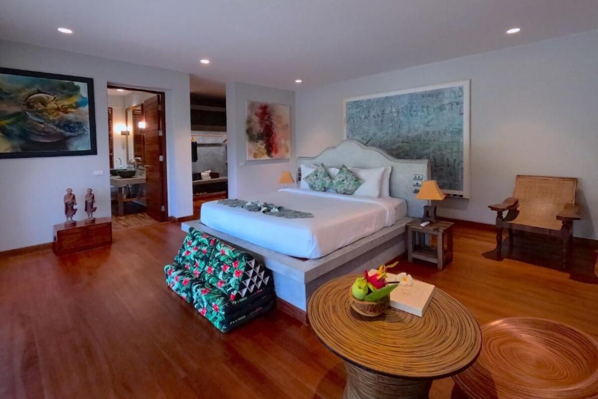 A spacious bedroom with a large bed, a dining table, and a chair.