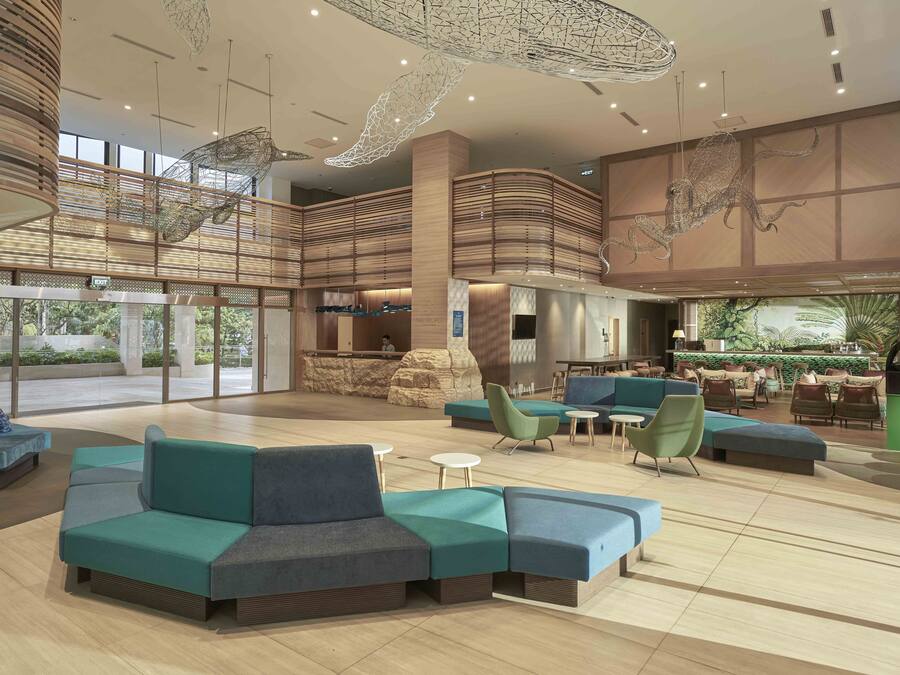 A spacious lobby with tiered seating areas, a central bar, and a large window offering a view of the outdoors.