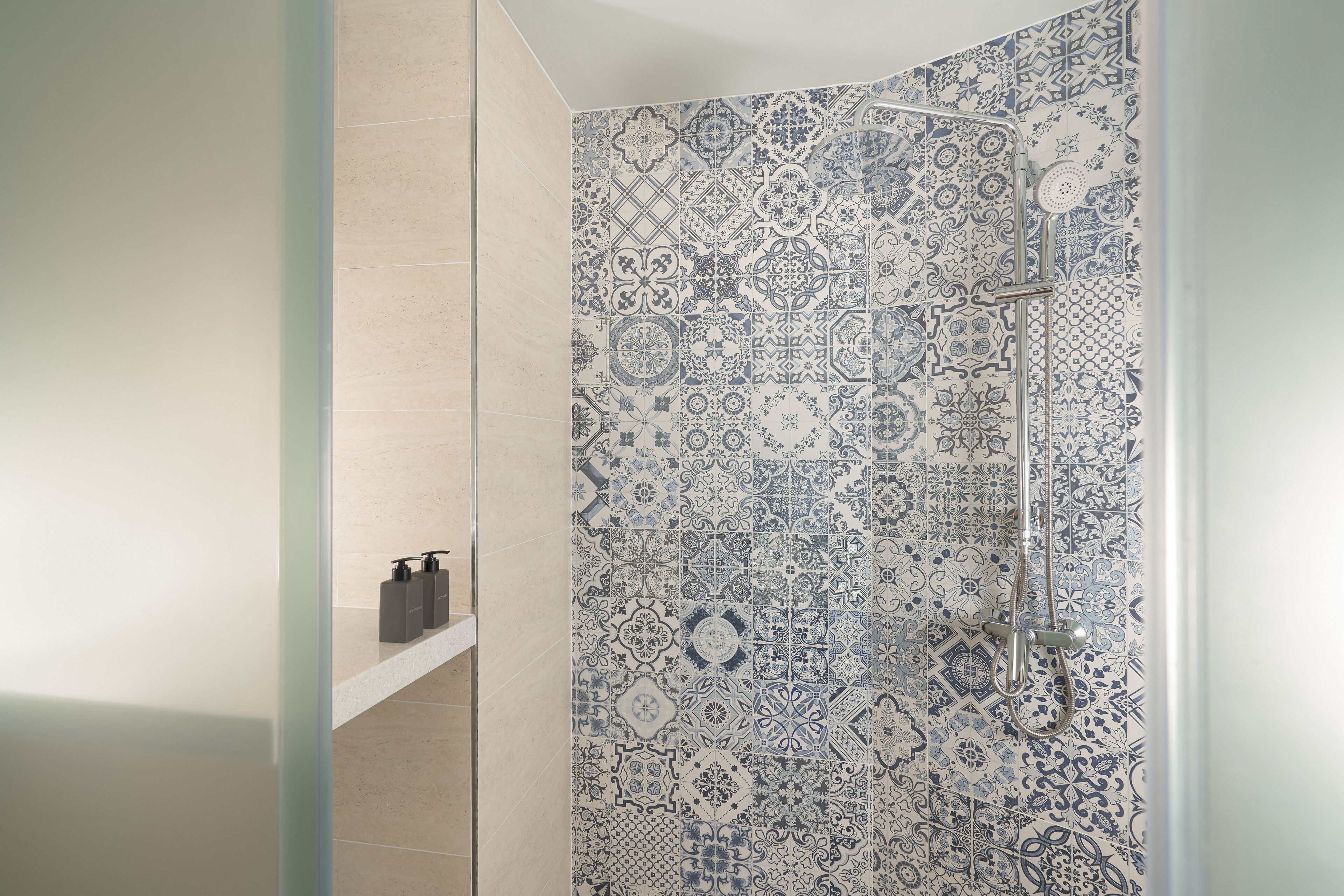 Une douche avec un motif complexe de carreaux et un pommeau de douche amovible.