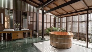A modern bathroom with a wooden bathtub, a large mirror, and a sink. - The Secret Con Dao (Ho Chi Minh City)