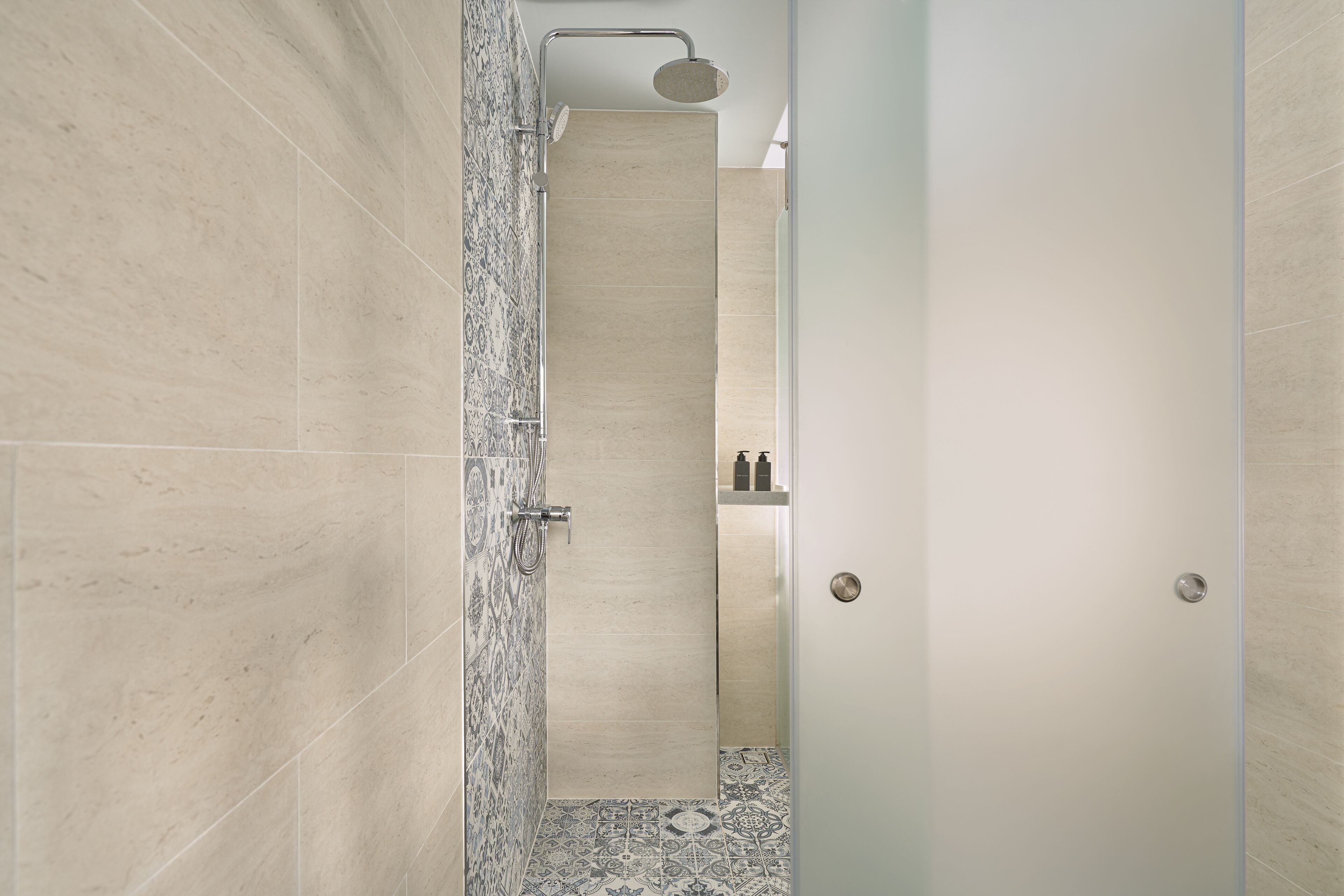 A modern bathroom with a shower, tiled walls, and a patterned floor.