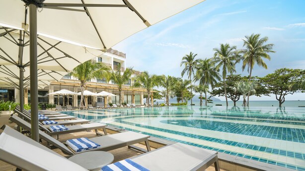 A poolside area with lounge chairs and umbrellas, a clear view of the sea, and palm trees. - The Secret Con Dao (Ho Chi Minh City)
