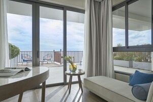 Una habitación moderna con balcón, sofá, una mesita con un florero y una silla.