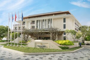 A modern hotel with a prominent entrance, multiple flags, and a landscaped garden area.