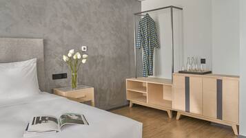 Una habitación de hotel moderna con una cama grande, una mesita de noche con un florero, un aparador de madera y un espejo.