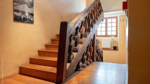 A wooden staircase with a handrail, a potted plant, and a window with a view of the outside.