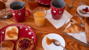 A breakfast setting with toast, jam, croissants, and beverages on a wooden table.