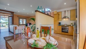 Una cocina moderna con comedor, que incluye una mesa de vidrio con pan y vino, y vistas al exterior.