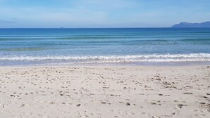 Una playa con cielo despejado y mar tranquilo.