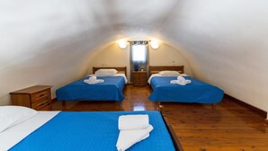 A room with two beds, wooden flooring, and a central light fixture. - Soulis Hotel (Santorini)