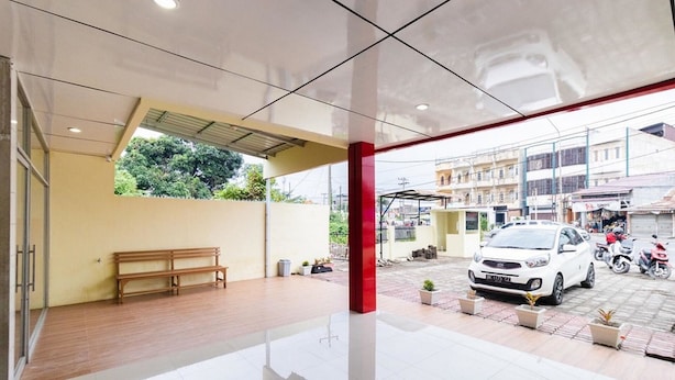 Un hall d’entrée propre et moderne, avec un banc, un pilier rouge et une vue sur la rue.