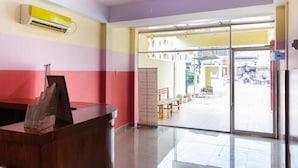 Un espace d’accueil avec un bureau en bois, une porte vitrée donnant sur l’extérieur et un appareil de climatisation fixé au mur.