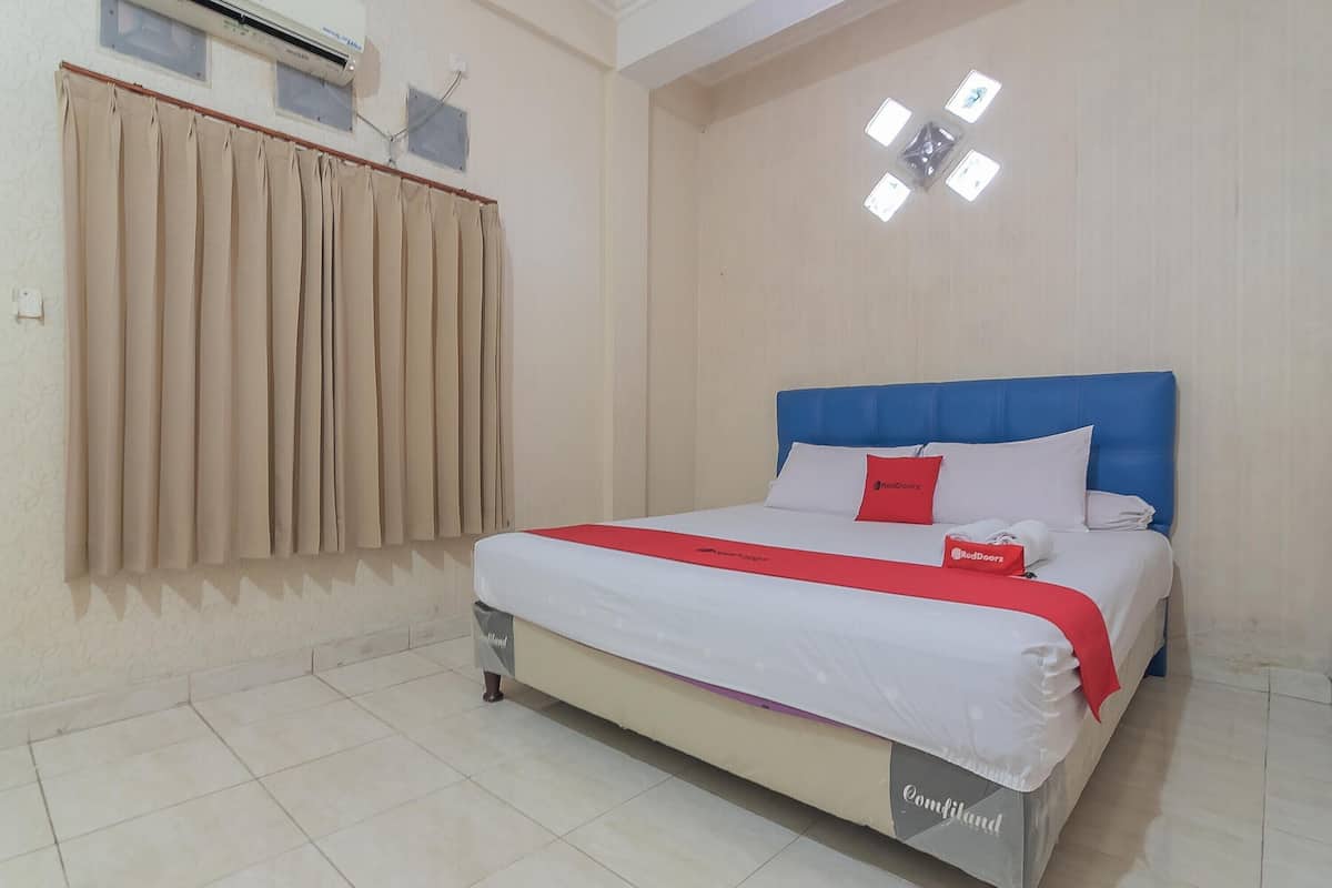 A hotel room with a bed, beige curtains, a ceiling light fixture, and a tiled floor.