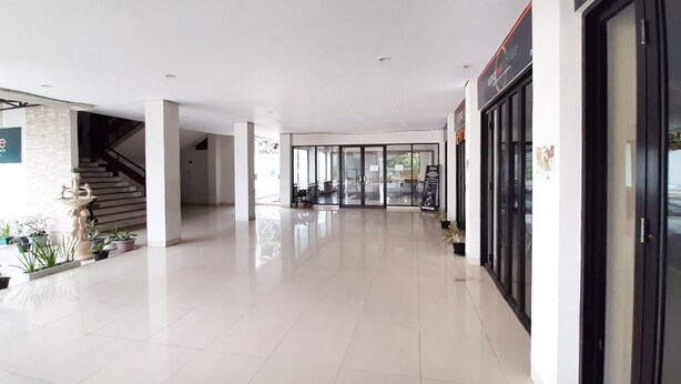 A spacious, modern lobby with a tiled floor, a staircase, and a glass entrance. - RedDoorz Plus @ Bitung City Center (Bitung)