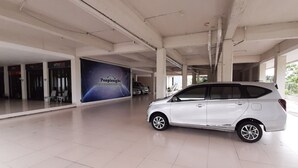 A white car parked in a spacious indoor area with a PeopleSight advertisement on the wall. - RedDoorz Plus @ Bitung City Center (Bitung)
