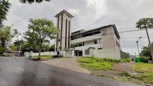 A modern building with a prominent tower, a gated entrance, and a sign indicating it is a hotel. - RedDoorz Plus @ Bitung City Center (Bitung)