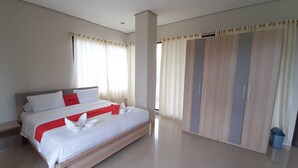 A spacious bedroom with a large bed, a wardrobe, and a trash bin. - RedDoorz Plus @ Bitung City Center (Bitung)