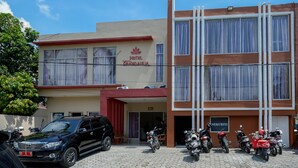 Ein Hotel mit roter und weißer Fassade, einer Beschilderung mit dem Aufschrift "HOTEL GRANDE AULA" und mehreren Motorrädern davor.