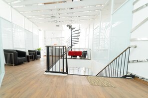 Un interior moderno con una escalera, suelo de madera y muebles negros.