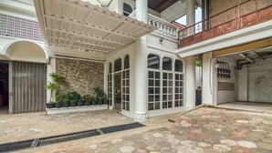 Un patio amplio con suelo de baldosas, una zona de estar cubierta y una pared de piedra.