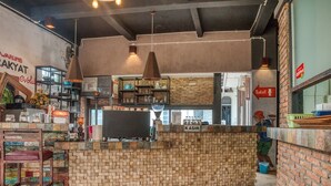 Interior de restaurante con mostrador de ladrillo, lámparas colgantes y un letrero visible para los baños.