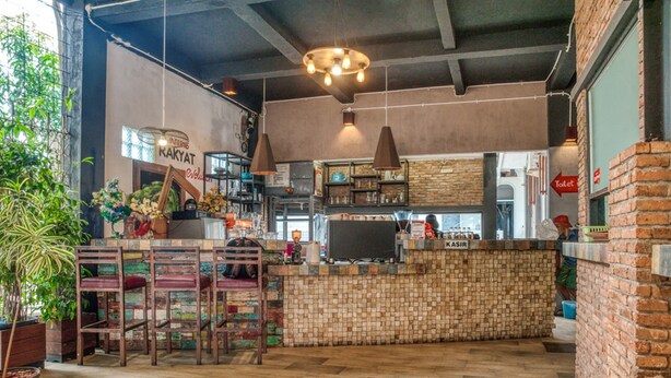 Un restaurante con mostrador de ladrillo, sillas de madera y una lámpara colgante.
