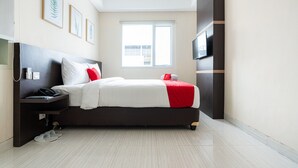 A modern hotel room with a bed, a TV, a nightstand, and a window. - RedDoorz Plus @ Harvest Inn Panakkukang (Makassar)