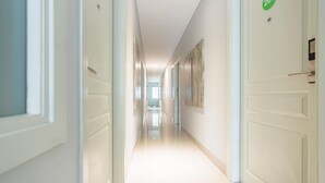 A bright, well-lit hallway with white doors, each marked with a number. - RedDoorz Plus @ Harvest Inn Panakkukang (Makassar)