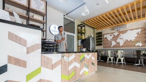 A reception area with a modern design, including a wooden reception desk, a world map on the wall, and a seating area with chairs. - RedDoorz Plus @ Harvest Inn Panakkukang (Makassar)