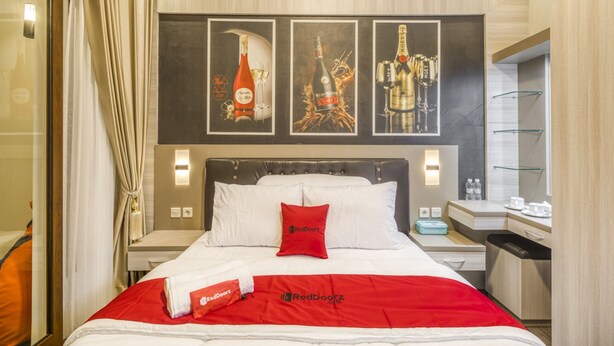 Una habitación de hotel con una cama, una mesita de noche, un escritorio y un espejo. Hay tres cuadros enmarcados en la pared sobre la cama.