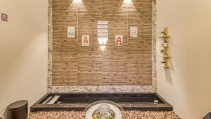 Un área de spa con pared de madera, fuente de agua y estante con plantas.