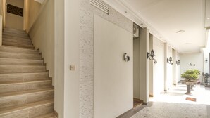 Un interior moderno con una escalera, un pasillo con pared estampada y una planta en maceta.