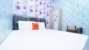 A hotel room with a bed, a wardrobe, and a small table. - KoolKost @ Menceng Raya (Jakarta)