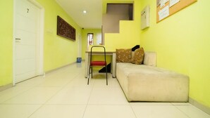 A room with a sofa, a chair, a desk, and a door. - KoolKost Syariah near TerasKota BSD (South Tangerang)