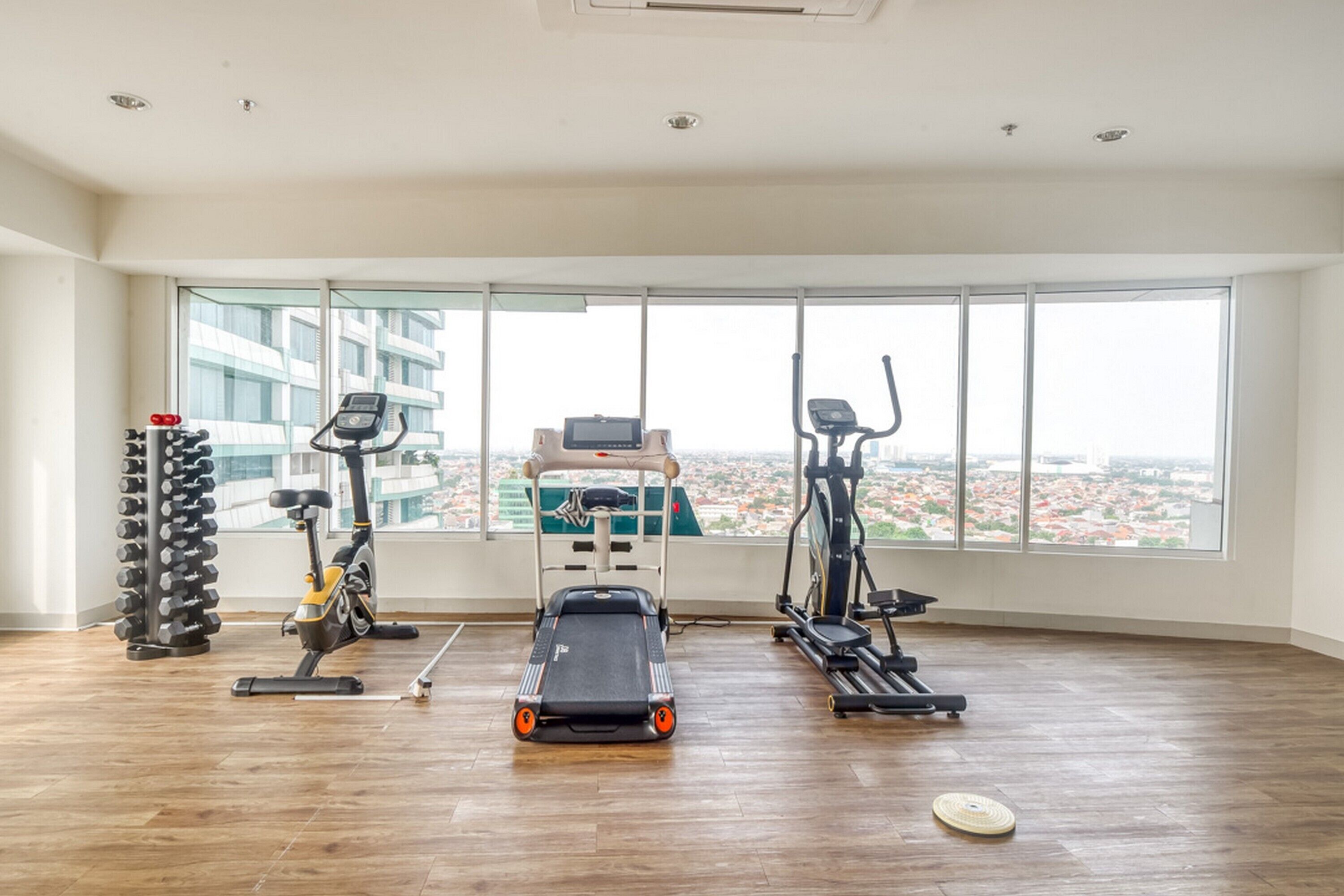 A spacious gym with cardio machines, dumbbells, and a treadmill.