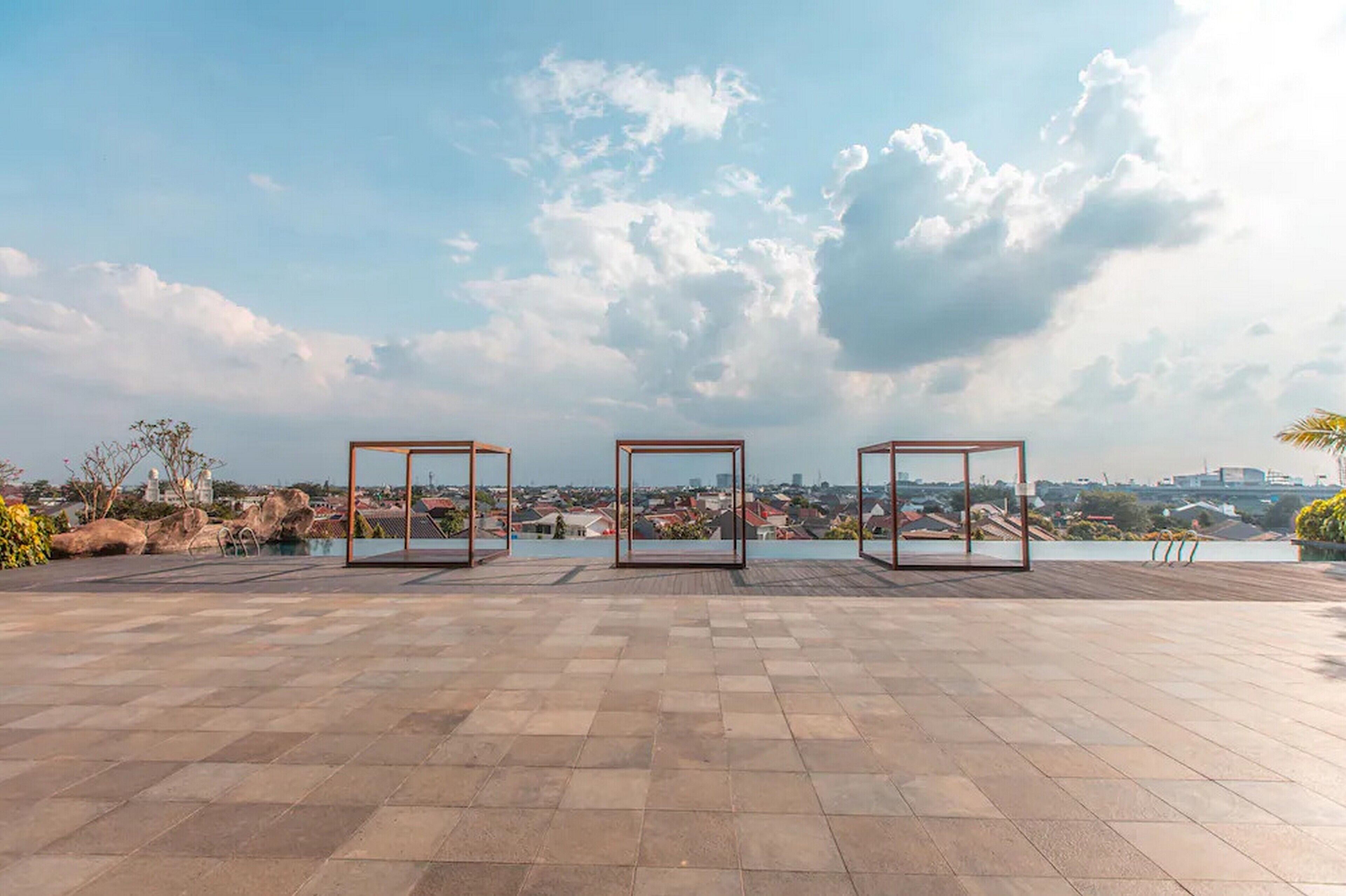 A rooftop terrace with three glass-enclosed seating areas, a pool, and a view of a cityscape.