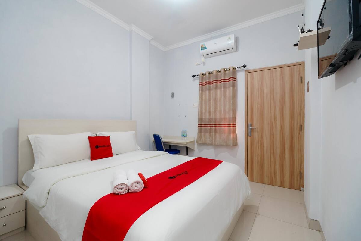 Ein Hotelzimmer mit Bett, Schreibtisch, Sessel, Fernseher und Kleiderschrank.