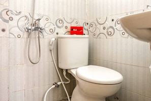 A bathroom with a toilet, a shower, and a sink.